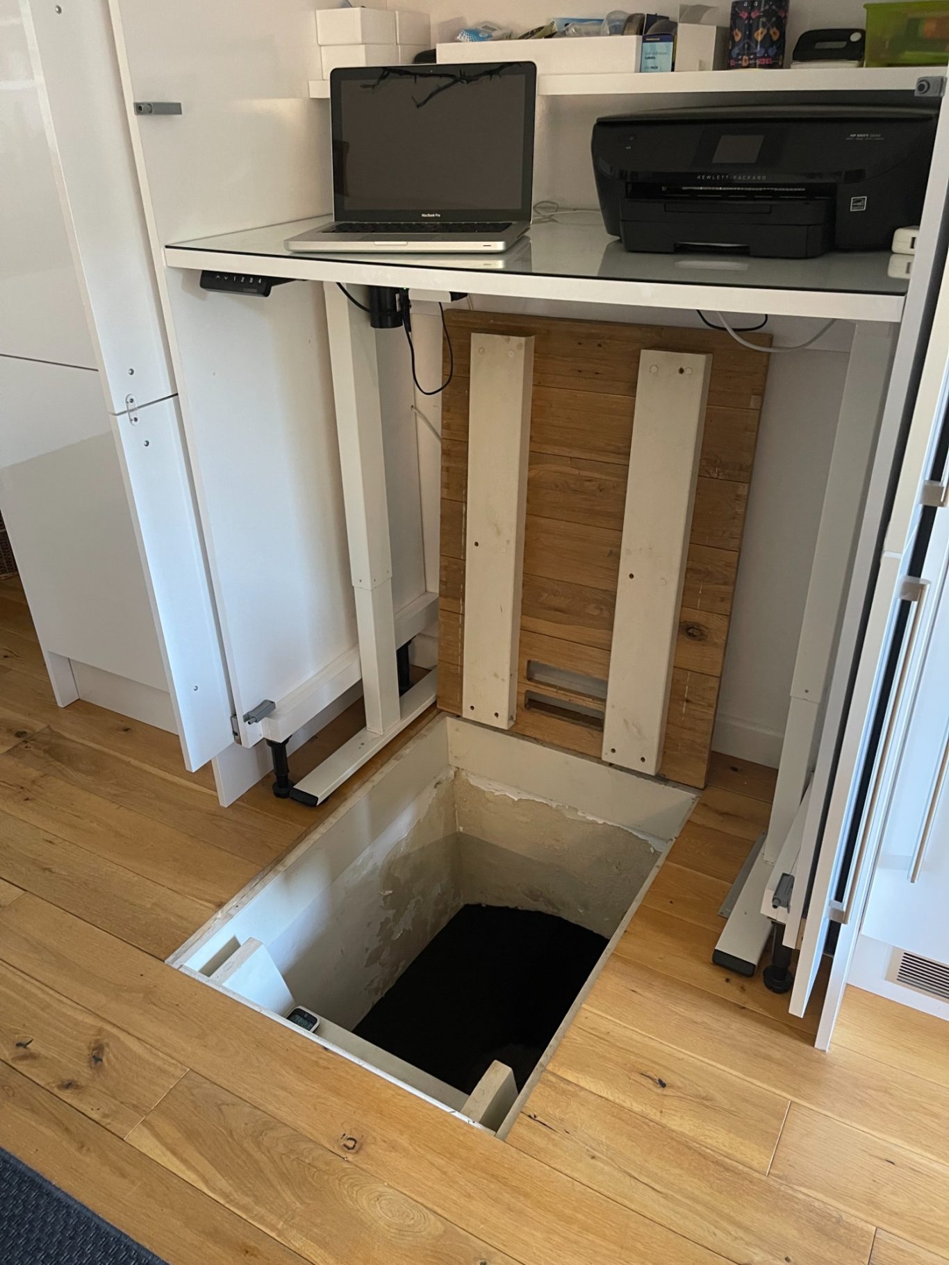 Cellar trap door open A hidden cellar trap door with a laptop and printer on a desk above it.