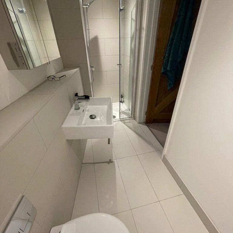 Modern bathroom featuring a shower, sink, and toilet with tiled flooring.