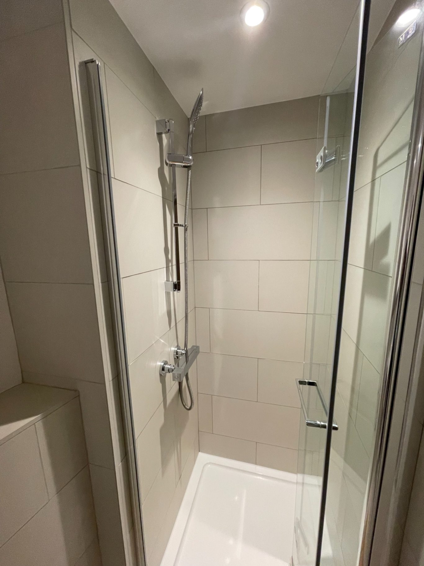 Modern shower enclosure with grey tiles and dual shower heads.