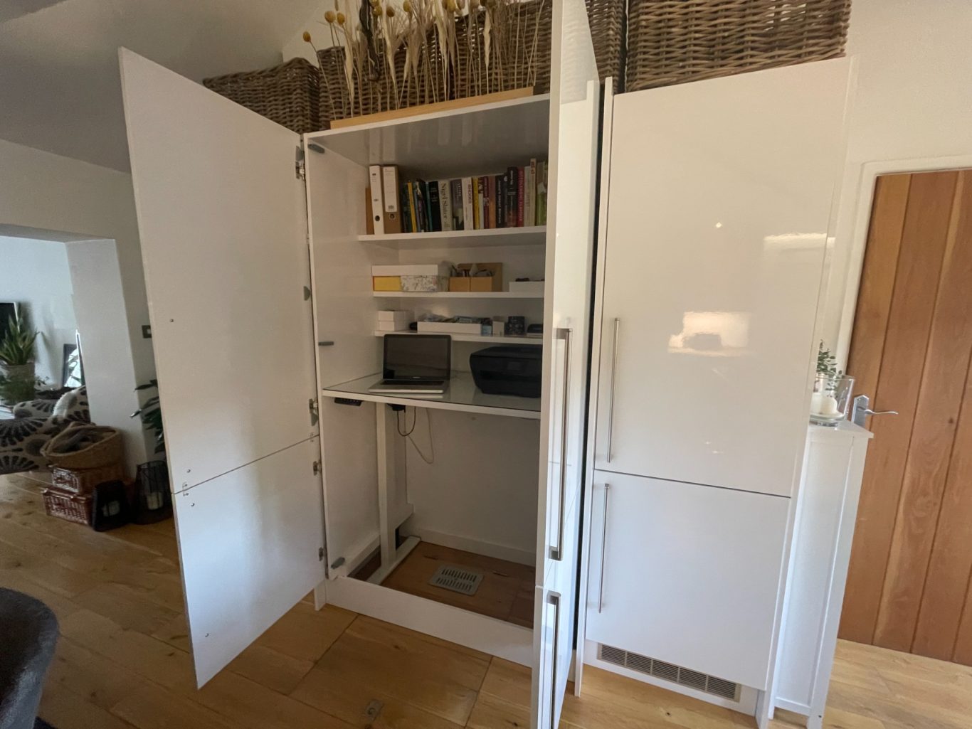 Kitchen units with pocket doors open A white cupboard with shelves containing books and storage boxes.